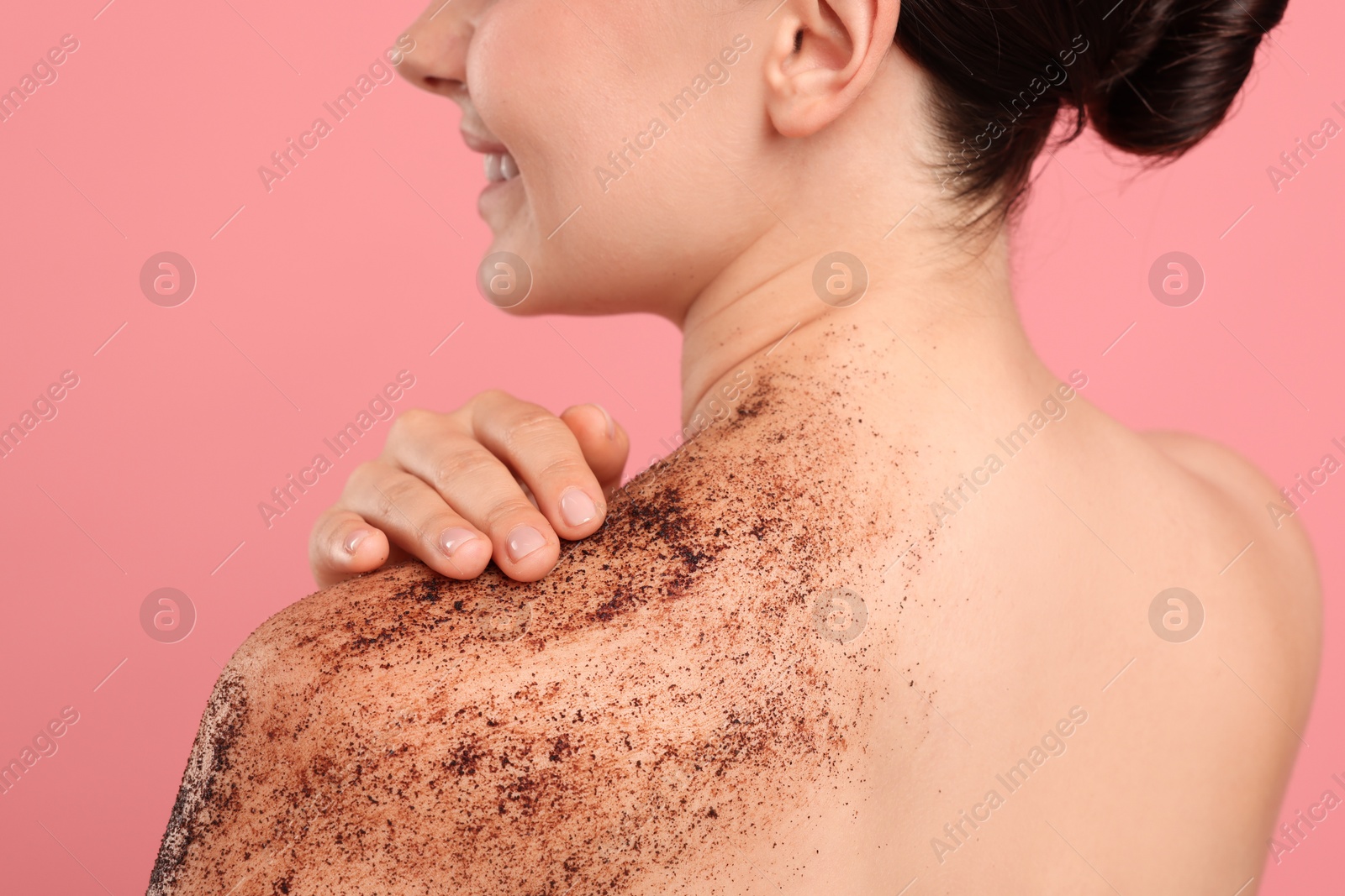 Smiling woman with body scrub on her shoulder against pink background Photo of Smiling woman with body scrub on her shoulder against pink background