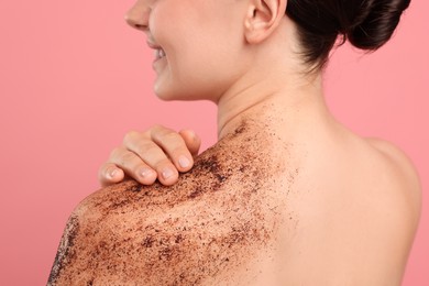 Photo of Smiling woman with body scrub on her shoulder against pink background