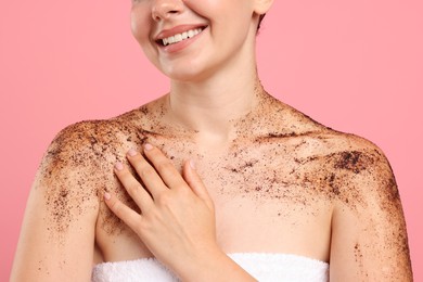 Photo of Smiling woman with body scrub on her skin against pink background, closeup