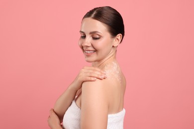 Photo of Smiling woman with body scrub on her skin against pink background