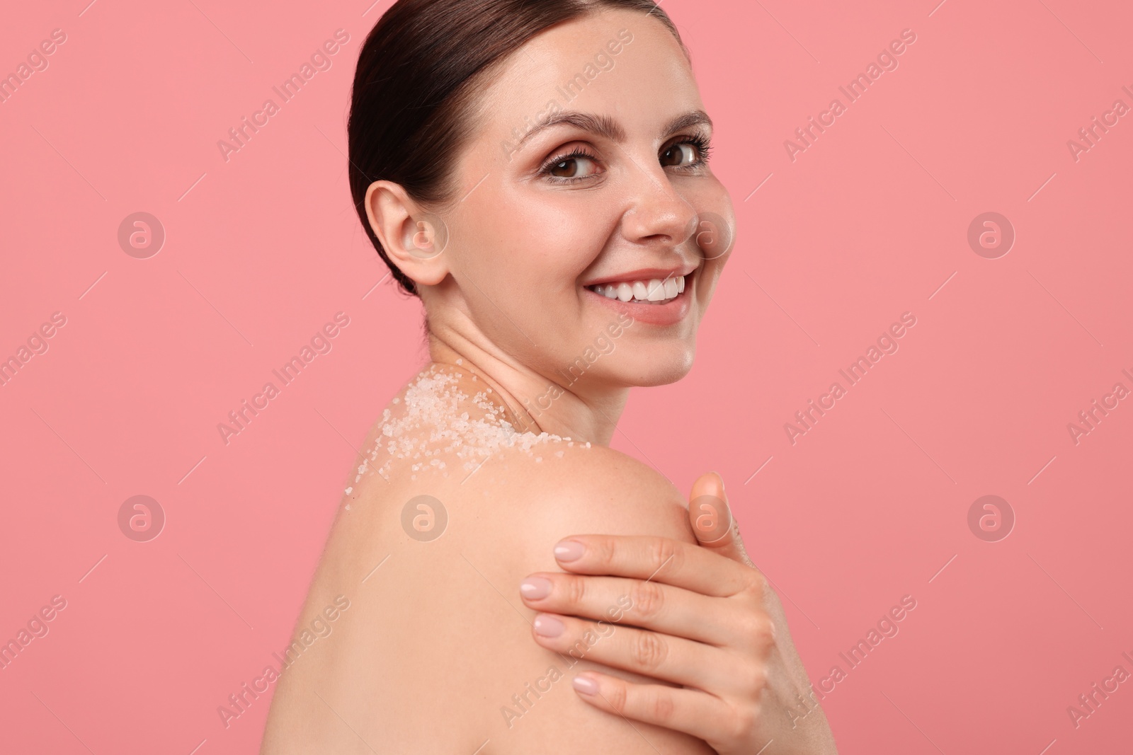 Smiling woman with body scrub on her skin against pink background Photo of Smiling woman with body scrub on her skin against pink background