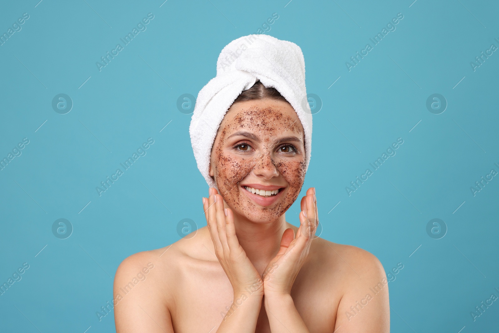 Photo of Smiling woman with body scrub on her face against light blue background