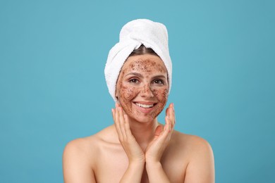 Photo of Smiling woman with body scrub on her face against light blue background