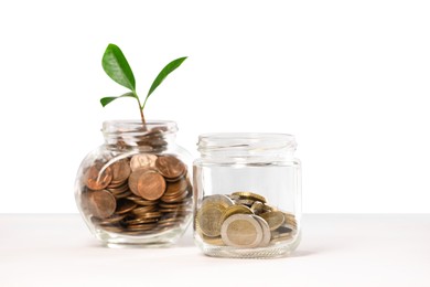 Photo of Investment concept. Glass jars with coins and sprout on light background