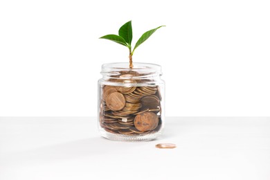 Photo of Investment concept. Glass jar with coins and sprout on light background