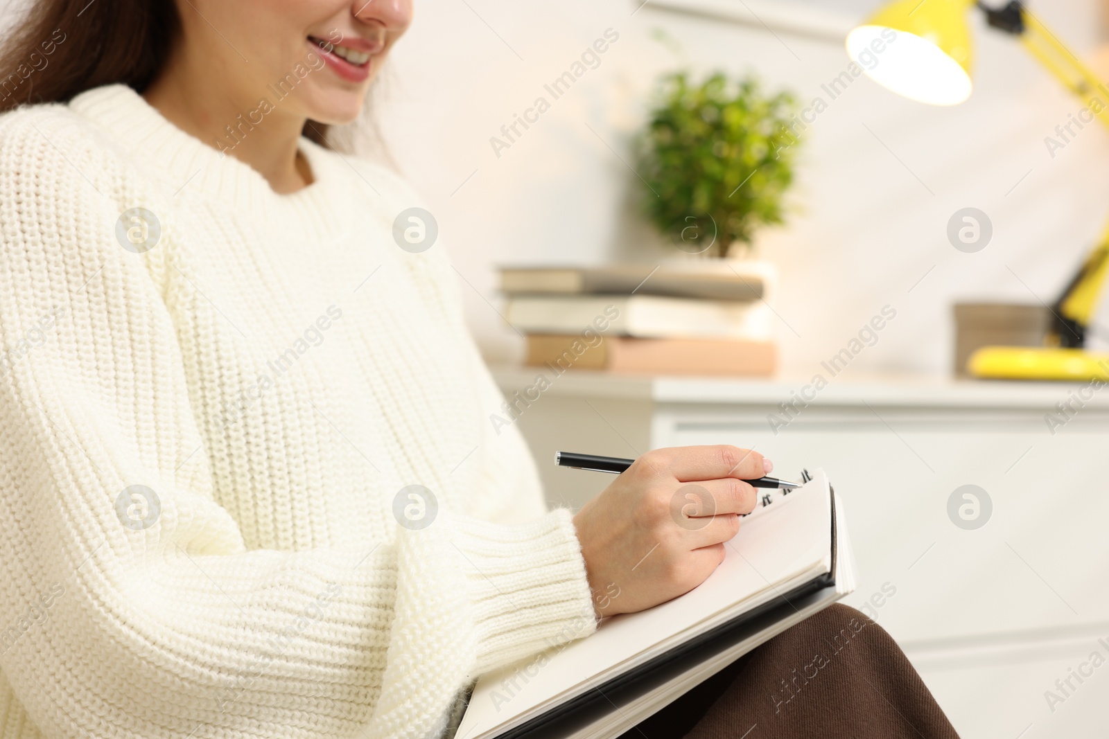 Woman writing in planner at home, closeup. Space for text Photo of Woman writing in planner at home, closeup. Space for text