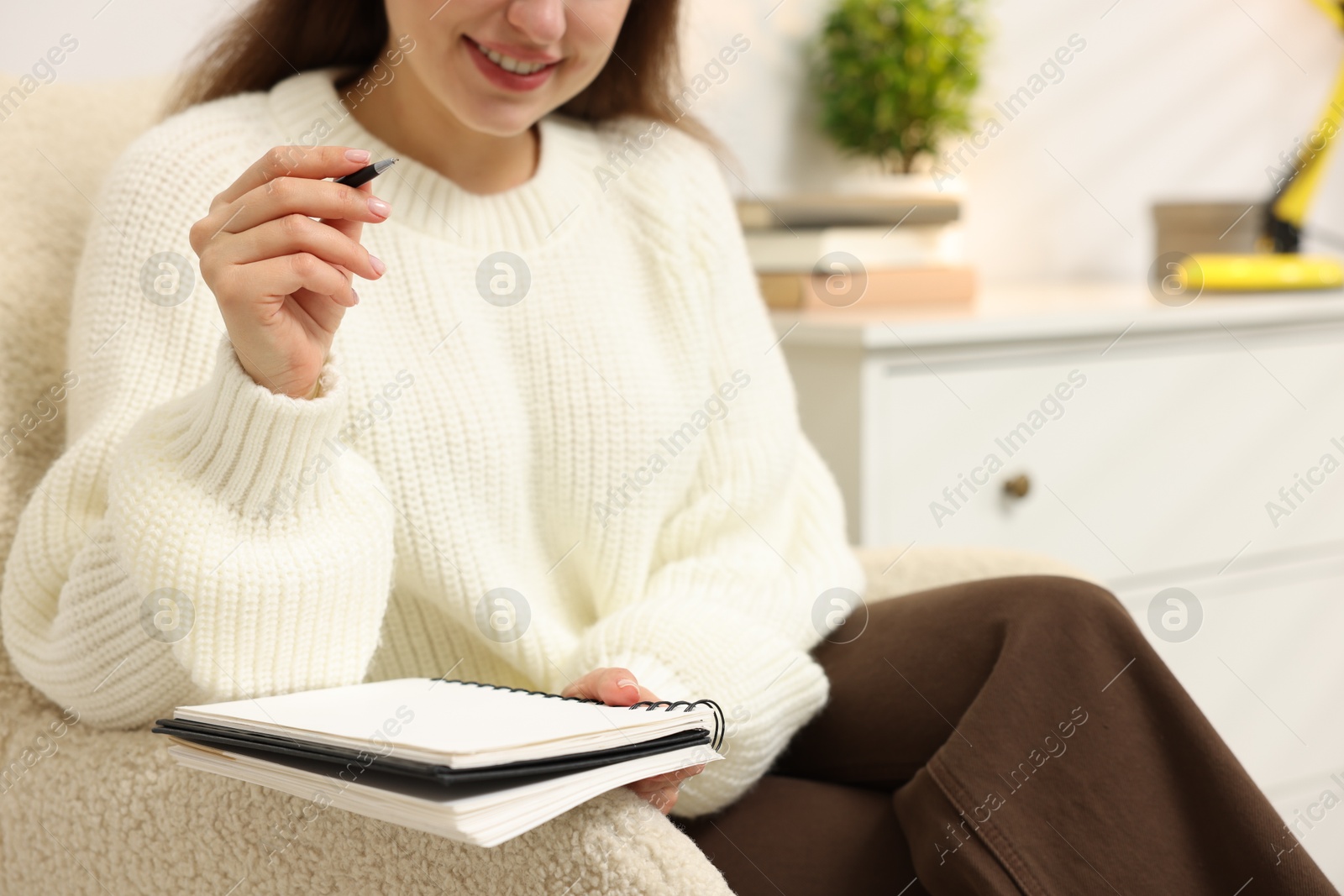 Woman with planner in armchair at home, closeup Photo of Woman with planner in armchair at home, closeup