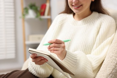 Photo of Woman writing in planner at home, closeup