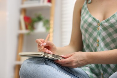 Photo of Woman writing in planner at home, closeup. Space for text
