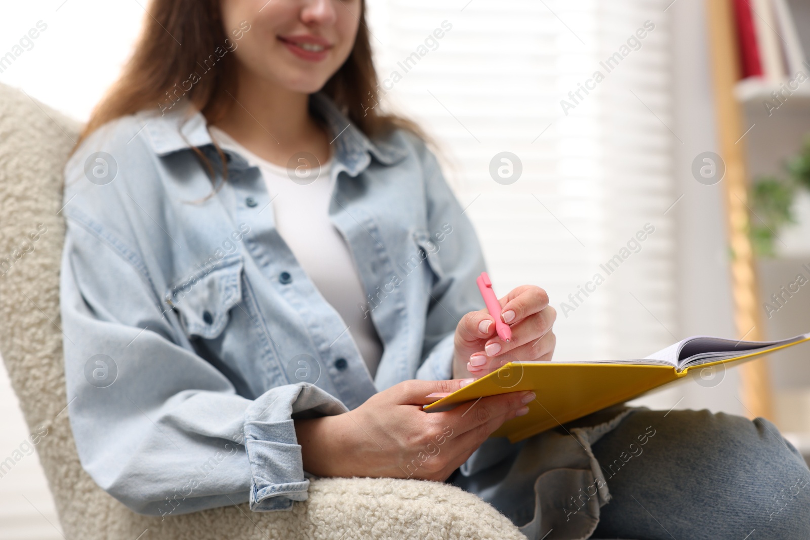 Woman writing in planner on armchair indoors, closeup. Space for text Photo of Woman writing in planner on armchair indoors, closeup. Space for text