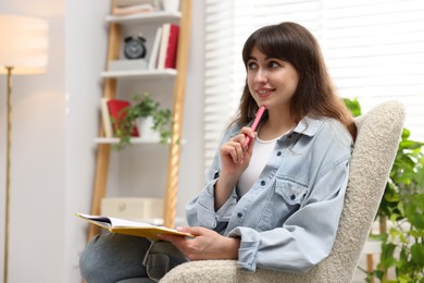 Photo of Woman with planner in armchair at home. Space for text