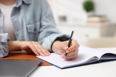 Photo of Woman writing in planner at white desk indoors, closeup. Space for text