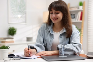 Photo of Woman with planner and laptop at white desk indoors. Space for text
