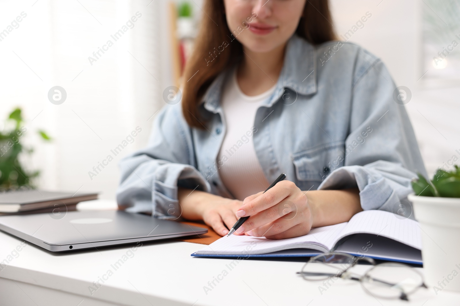 Woman with planner and laptop at white desk indoors, closeup Photo of Woman with planner and laptop at white desk indoors, closeup