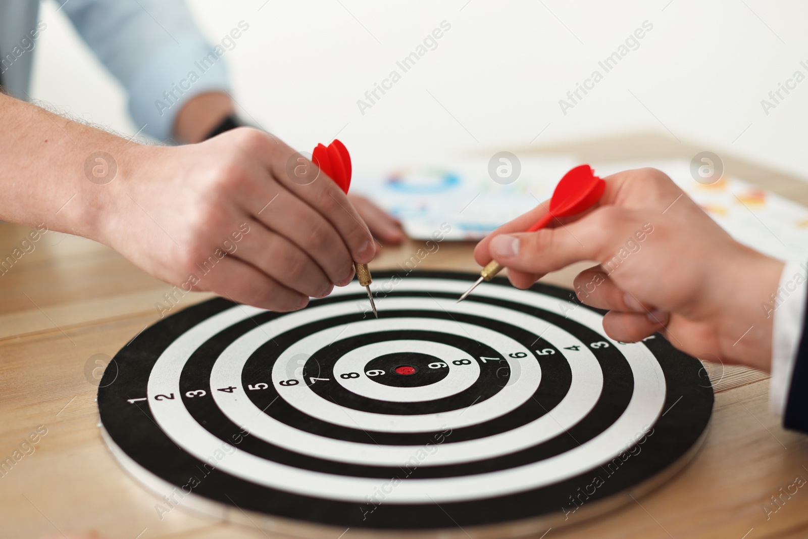 Photo of Men with darts aiming at dartboard indoors, closeup