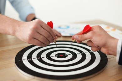 Photo of Men with darts aiming at dartboard indoors, closeup