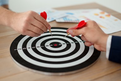 Photo of Men with darts aiming at dartboard indoors, closeup