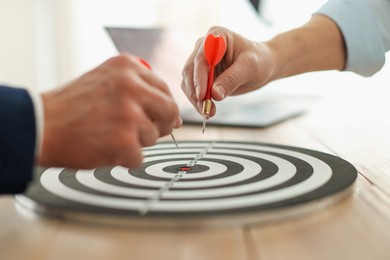 Photo of Men with darts aiming at dartboard indoors, closeup