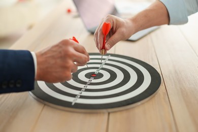 Photo of Men with darts aiming at dartboard indoors, closeup
