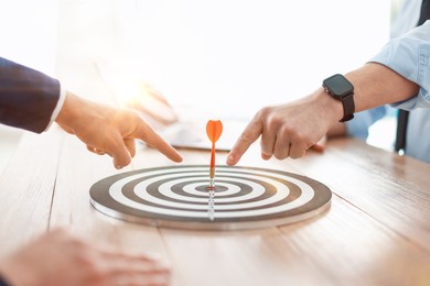 Photo of Men pointing at dartboard at wooden table indoors, closeup