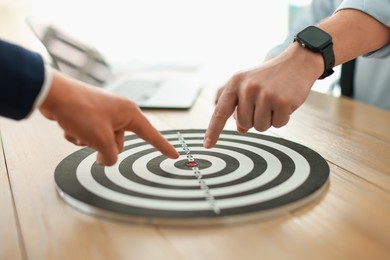 Photo of Men pointing at dartboard at wooden table indoors, closeup