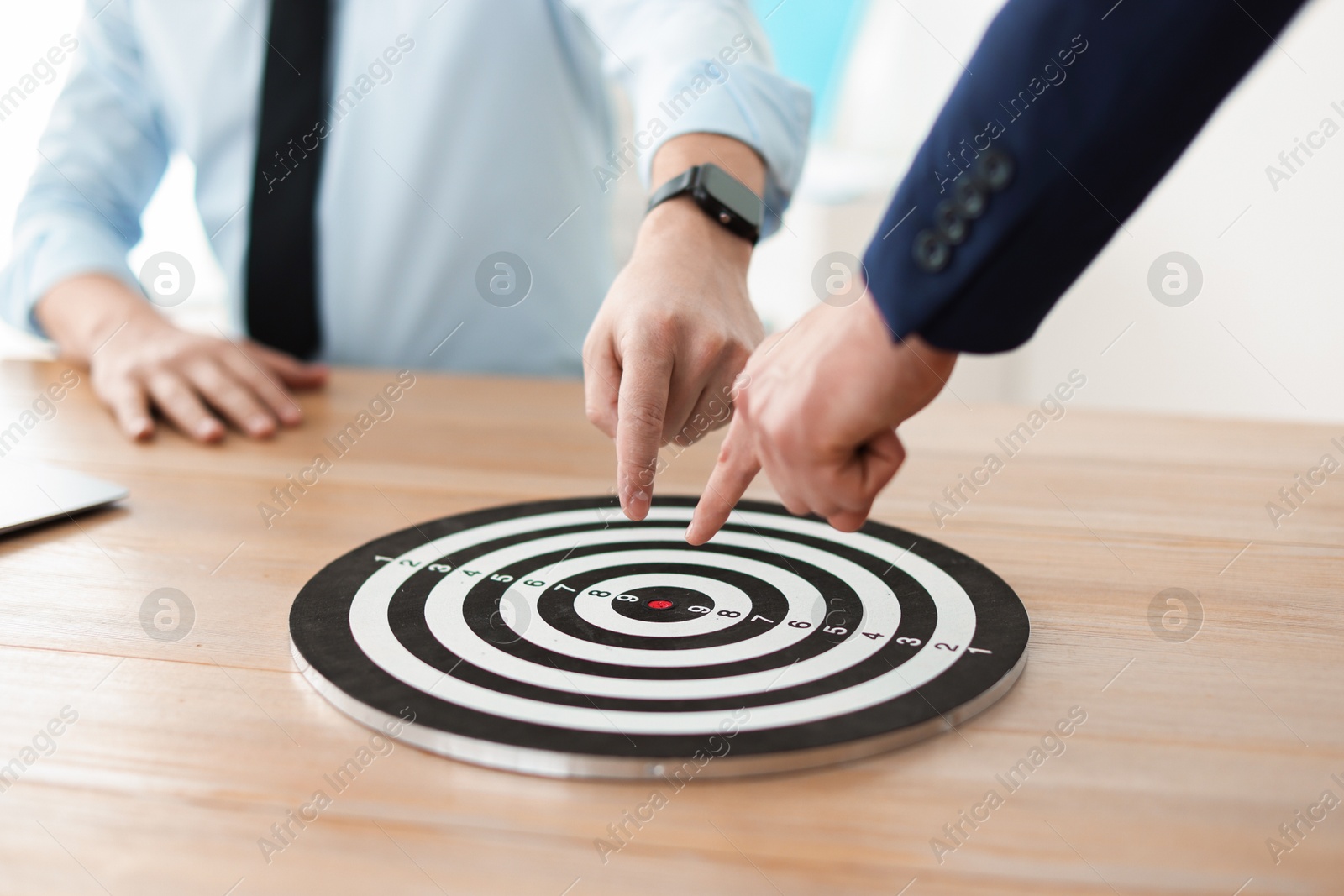 Photo of Men pointing at dartboard at wooden table indoors, closeup