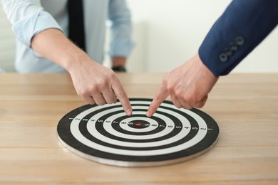 Photo of Men pointing at dartboard at wooden table indoors, closeup