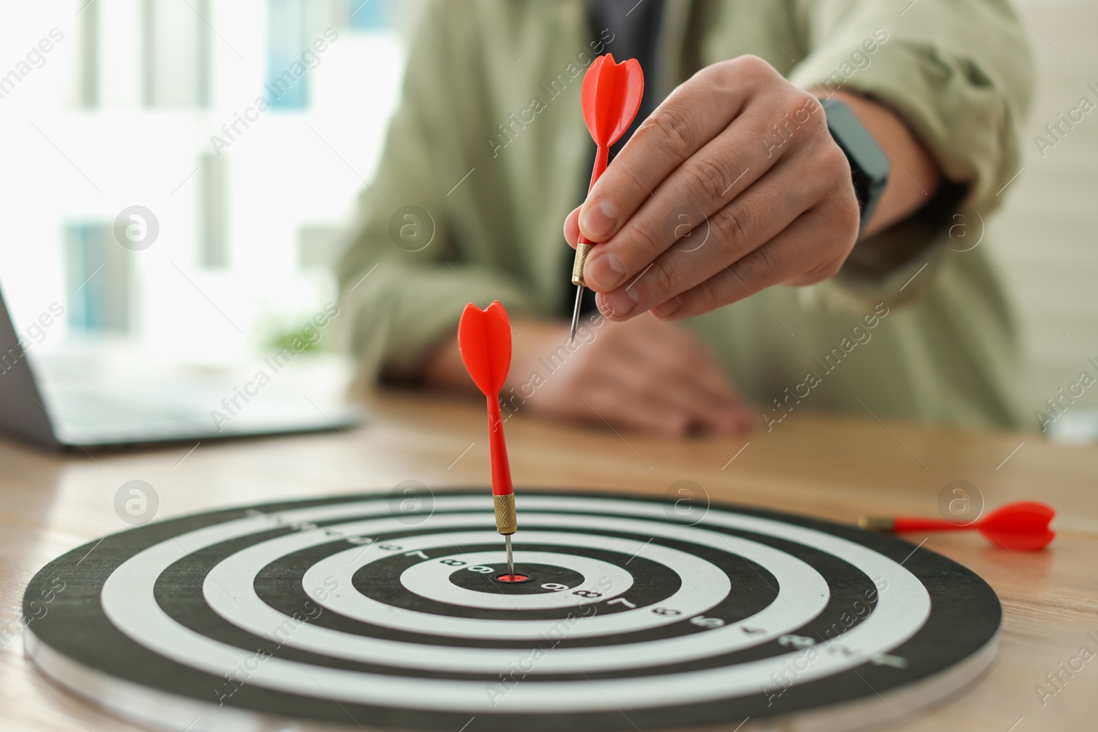 Photo of Man with dart aiming at dartboard while working indoors, closeup