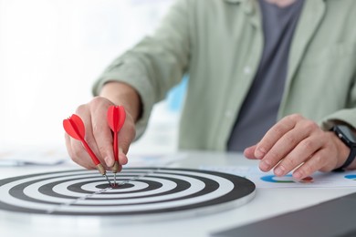 Photo of Man with dart aiming at dartboard indoors, closeup