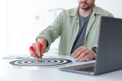 Photo of Man with dart aiming at dartboard indoors, closeup