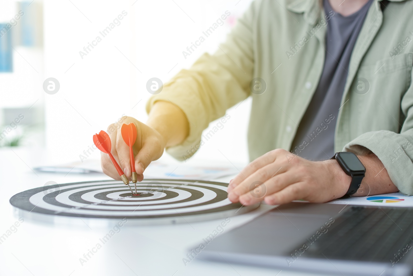 Photo of Man with dart aiming at dartboard indoors, closeup