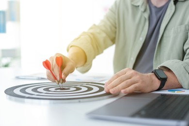 Photo of Man with dart aiming at dartboard indoors, closeup