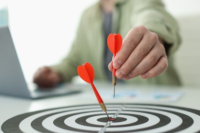 Photo of Man with dart aiming at dartboard while working indoors, closeup