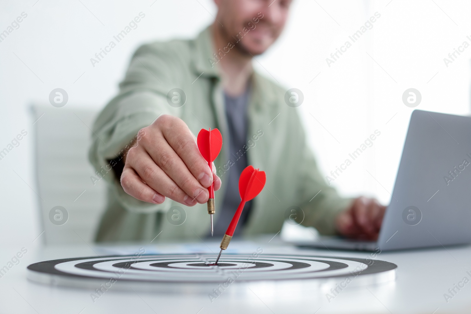 Man with dart aiming at dartboard while working indoors, closeup Photo of Man with dart aiming at dartboard while working indoors, closeup