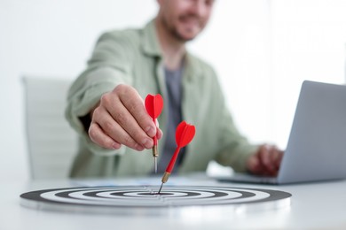 Photo of Man with dart aiming at dartboard while working indoors, closeup