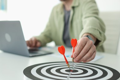 Photo of Man with dart aiming at dartboard while working indoors, closeup