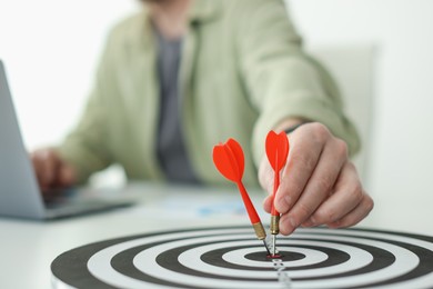 Photo of Man with dart aiming at dartboard while working indoors, closeup