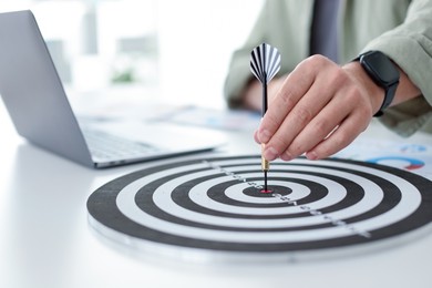 Photo of Man with dart aiming at dartboard while working indoors, closeup