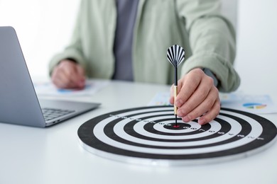 Photo of Man with dart aiming at dartboard while working indoors, closeup