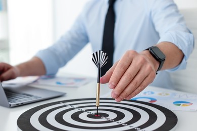 Photo of Man with dart aiming at dartboard while working indoors, closeup