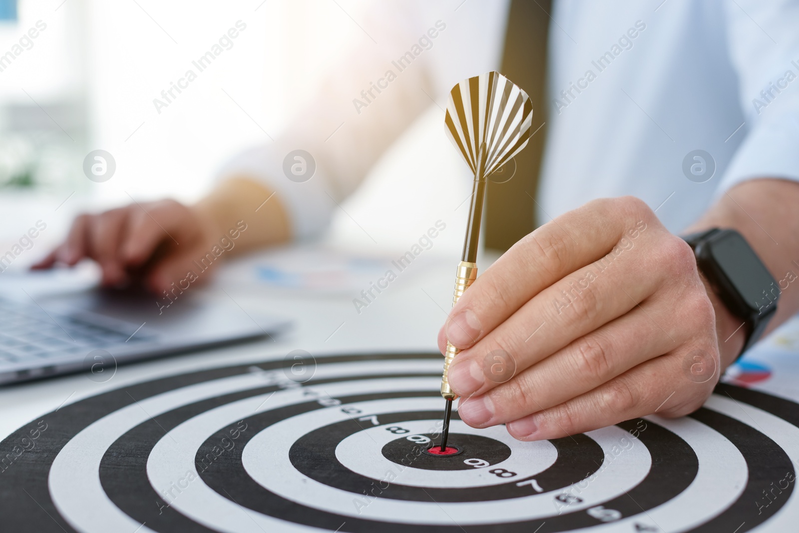 Photo of Man with dart aiming at dartboard while working indoors, closeup