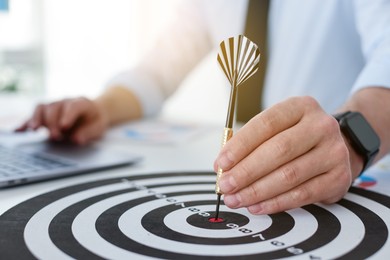 Photo of Man with dart aiming at dartboard while working indoors, closeup