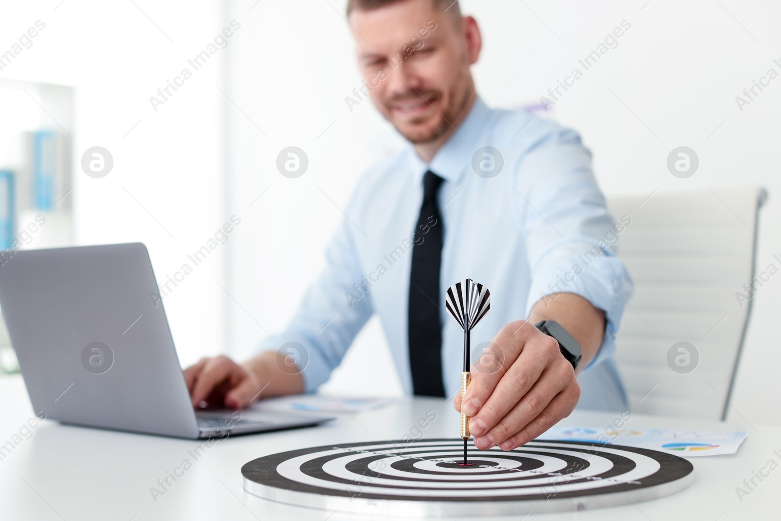 Man with dart aiming at dartboard while working indoors, selective focus Photo of Man with dart aiming at dartboard while working indoors, selective focus