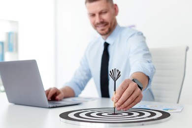 Photo of Man with dart aiming at dartboard while working indoors, selective focus