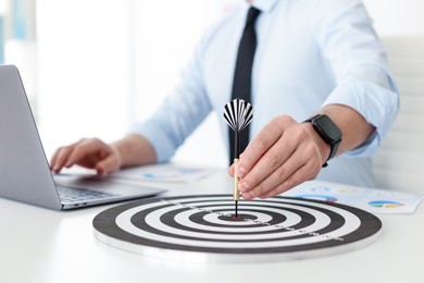Photo of Man with dart aiming at dartboard while working indoors, closeup