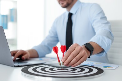 Photo of Man with dart aiming at dartboard while working indoors, closeup
