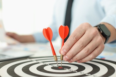 Photo of Man with dart aiming at dartboard while working indoors, closeup