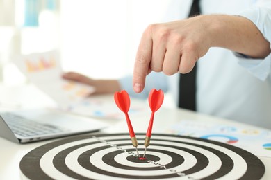 Photo of Man pointing at dartboard while working at table indoors, closeup