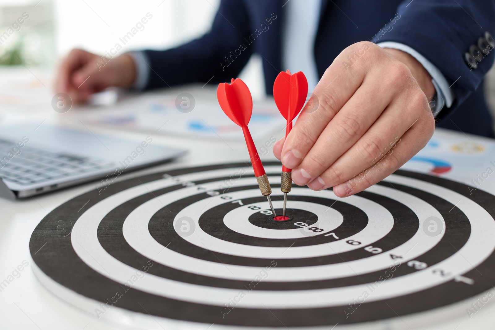 Photo of Man with dart aiming at dartboard while working indoors, closeup