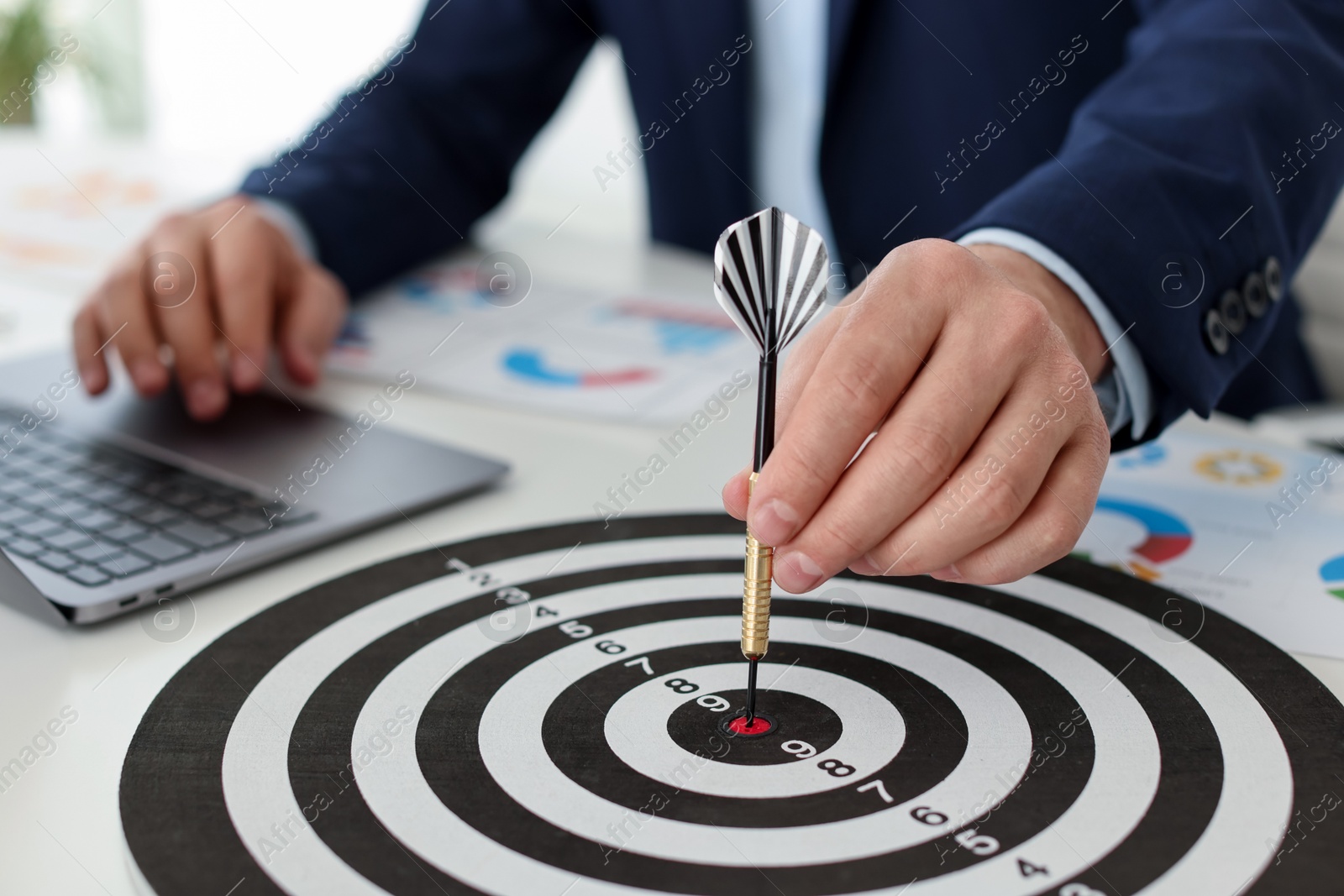 Photo of Man with dart aiming at dartboard while working indoors, closeup